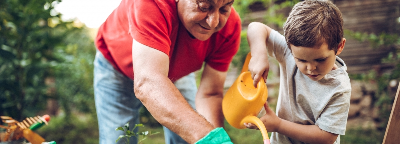 man watering plants with child